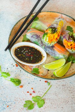 Pirinç kağıdı, çiğ sebze ve açık mavi arka planda acı soslu bitkilerden yapılmış taze Asya aperatifli börekler (Nem). Vietnam Yemekleri