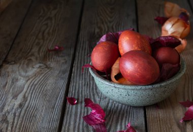 Haşlanmış yumurta, ahşap arka planda soğan kabuğuyla boyanmış..