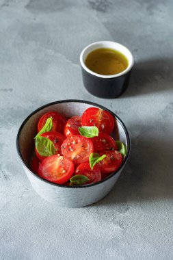 Gri arka planda taze vişneli domates salatası, kızarmış ekmek, fesleğen yaprağı, baharat ve aromalı zeytinyağı. Panzanella yazın popüler bir Toskana sebze salatasıdır. İtalyan Mutfağı.