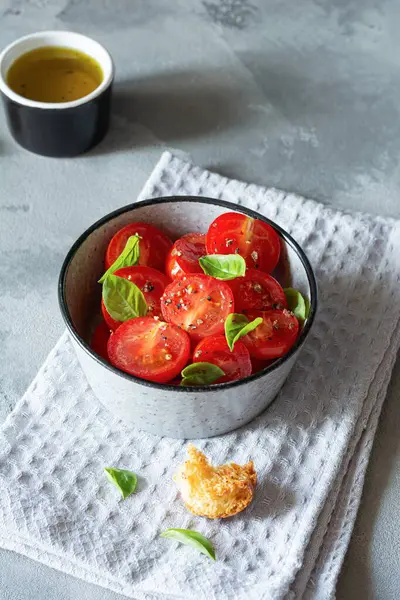 Gri arka planda taze vişneli domates salatası, kızarmış ekmek, fesleğen yaprağı, baharat ve aromalı zeytinyağı. Panzanella yazın popüler bir Toskana sebze salatasıdır. İtalyan Mutfağı.