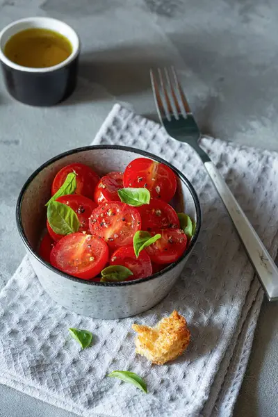Gri arka planda taze vişneli domates salatası, kızarmış ekmek, fesleğen yaprağı, baharat ve aromalı zeytinyağı. Panzanella yazın popüler bir Toskana sebze salatasıdır. İtalyan Mutfağı.