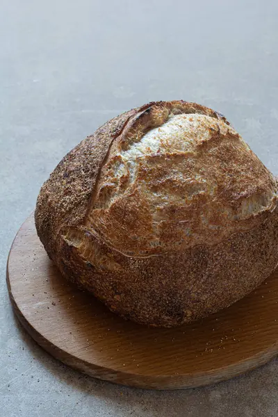 Gri bir arka planda tam buğday unu eklenmiş taze kabuklu ekşi ekmek. Mayasız ekmek, Tartine, sağlıklı yemek..