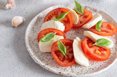Caprese salad with juicy tomatoes, fresh mozzarella and pesto. Concept for a tasty and healthy appetizer, flat lay. Italian food, cuisine.