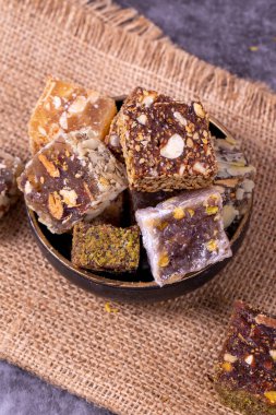 Koyu arkaplanda Türk lezzeti çeşitleri var. Fıstık, fındık ve meyve aromalı Türk tatları. Kapat.