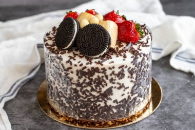 Koyu arkaplanda meyve ve bisküvi parçaları olan kek. Kapat.