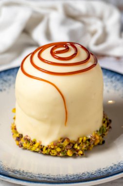 Beyaz ahşap arka planda şam fıstıklı karamel kek. Pastane tatlıları. Kapat.