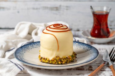 Beyaz ahşap arka planda şam fıstıklı karamel kek. pastane tatlıları