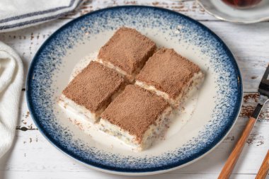 Beyaz ahşap arka planda soğuk baklava. Sütlü ve fıstıklı baklava. Akdeniz mutfağı lezzetlidir. Kapat.