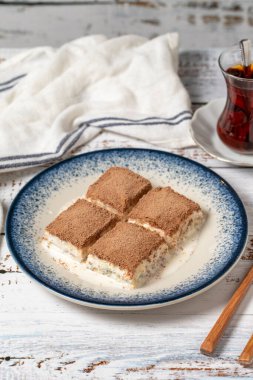 Beyaz ahşap arka planda soğuk baklava. Sütlü ve fıstıklı baklava. Akdeniz mutfağı lezzetlidir. Kapat.