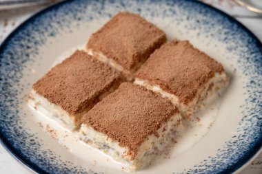 Beyaz ahşap arka planda soğuk baklava. Sütlü ve fıstıklı baklava. Akdeniz mutfağı lezzetlidir. Kapat.