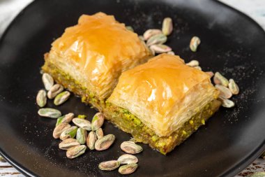 Beyaz ahşap arka planda fıstıklı baklava. Türk mutfağı lezzetleri. Türk baklavası. Kapat.