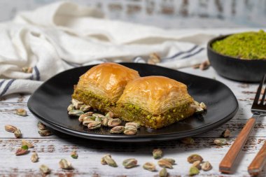 Beyaz ahşap arka planda fıstıklı baklava. Türk mutfağı lezzetleri. Türk baklavası. Kapat.