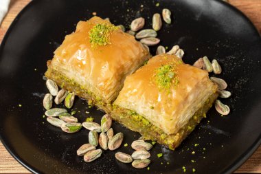 Ahşap arka planda fıstıklı baklava. Türk mutfağı lezzetleri. Türk baklavası. Kapat.