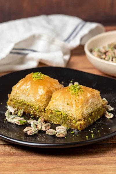 Ahşap arka planda fıstıklı baklava. Türk mutfağı lezzetleri. Türk baklavası. Kapat.