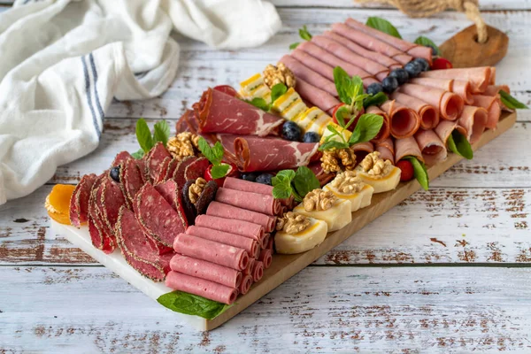 Cold Smoked Meat Plate on wood floor. Antipasto set plater wooden plate. Cold smoked meat with prosciutto, salami, bacon, veal cutlet
