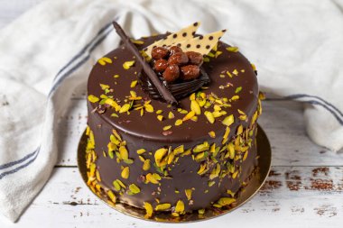 Fıstıklı ve çikolatalı pasta. Beyaz ahşap arka planda kutlama ya da doğum günü pastası. Kapat.