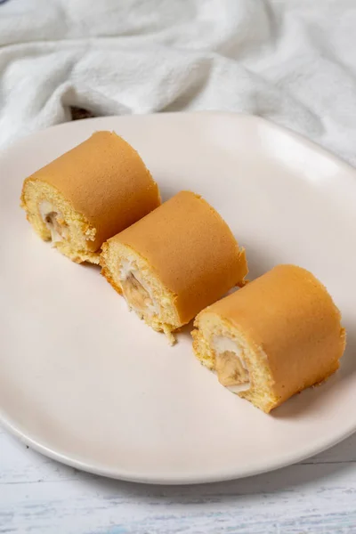 Banana roll cake. Snack roll cake on a white wood background. close up