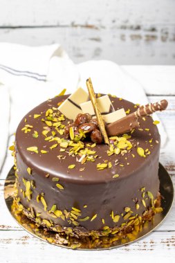 Çikolatalı ve şam fıstıklı kek. Ahşap zeminde doğum günü veya kutlama pastası. Kapat.