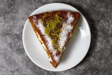 Koyu arkaplanlı kremalı kadayif tatlısı. Türk mutfağı tatlısı. Üst Manzara. Kapat.