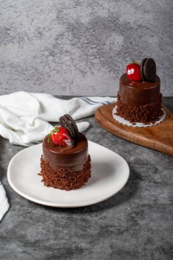 Koyu arkaplanda çikolatalı ve çilekli pasta. Bisküvi, çikolata ve özel kremayla hazırlanmış meyveli pasta. Fırın ürünleri