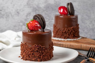 Koyu arkaplanda çikolatalı ve çilekli pasta. Bisküvi, çikolata ve özel kremayla hazırlanmış meyveli pasta. Fırın ürünleri