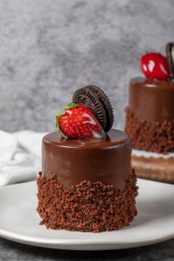 Koyu arkaplanda çikolatalı ve çilekli pasta. Bisküvi, çikolata ve özel kremayla hazırlanmış meyveli pasta. Fırın ürünleri