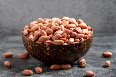 Fıstıklar koyu arkaplanda kasede. Hindistan cevizi kasesinde fıstık kabuğu. Kapat.