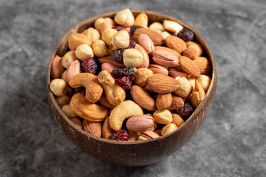 Arka planda kabın içinde fındık var. Hindistan cevizi kasesinde fındık, kaju, badem ve şam fıstığı. Kapat.