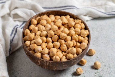 Gri arka planda kavrulmuş fındıklar. Hindistan cevizi kasesinde fındık. Kapat.