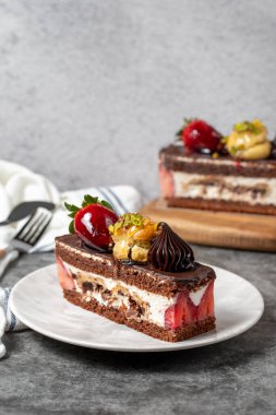 Koyu arkaplanda çilekli ve çikolatalı pasta. Bir dilim çikolatalı pasta. Pasta ürünleri. Kapat.