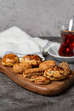 Koyu arkaplanda tuzlu kurabiyeler. Tahta servis tabağında susam ve tohum kurabiyeleri. Kapat.