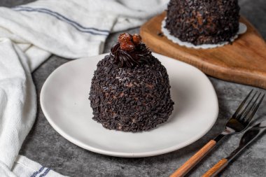 Koyu arkaplanda çikolata ve fıstıklı kek. Kremalı lezzetli pasta. Stüdyo çekimi. Fırın ürünleri. Kapat.