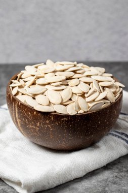 Koyu arkaplanda kabak tohumları. Hindistan cevizi kabuğunda kabak çekirdeği. Kapat.