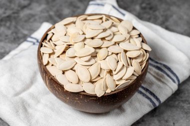 Koyu arkaplanda kabak tohumları. Hindistan cevizi kabuğunda kabak çekirdeği. Kapat.