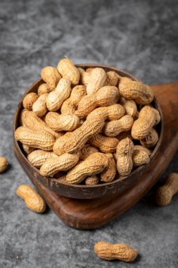Arka planda kabuklu fıstıklar. Hindistan cevizi kasesinde yer fıstığı. Kapat.