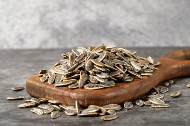 Koyu arkaplanda kabuklu ayçekirdeği. Tahta sunum tahtasında tuzlu ayçekirdeği. Kapat.