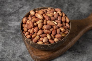 Karanlık arka planda yer fıstıkları. Hindistan cevizi kasesinde yer fıstığı. Stüdyo çekimi. Kapat.