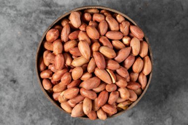 Karanlık arka planda yer fıstıkları. Hindistan cevizi kasesinde yer fıstığı. Stüdyo çekimi. Üst görünüm