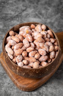 Karanlık arka planda tuzlu fıstık. Hindistan cevizi kasesinde yer fıstığı. Stüdyo çekimi. Kapat.