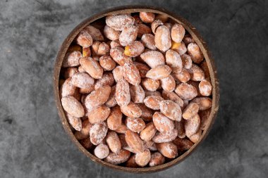 Karanlık arka planda tuzlu fıstık. Hindistan cevizi kasesinde yer fıstığı. Stüdyo çekimi. Üst görünüm