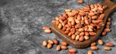 Karanlık arka planda yer fıstıkları. Ahşap servis tahtasındaki fıstıklar. Stüdyo çekimi. Metin için boş alan. Boşluğu kopyala