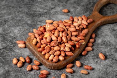 Karanlık arka planda yer fıstıkları. Ahşap servis tahtasındaki fıstıklar. Stüdyo çekimi. Kapat.