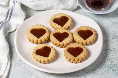 Heart shaped cookies on plate on gray background. Cookies with marmalade filling in the middle. Bakery desserts. close up