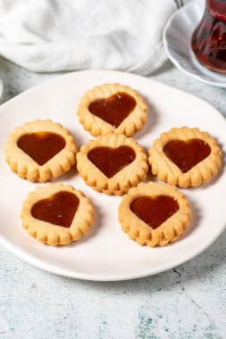 Heart shaped cookies on plate on gray background. Cookies with marmalade filling in the middle. Bakery desserts. close up