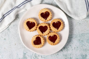Heart shaped cookies on plate on gray background. Cookies with marmalade filling in the middle. Bakery desserts. Top view