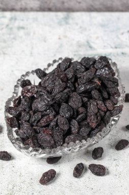 Dried black grapes on stone background. Dried grapes in glass bowl. Nuts varieties. Healthy eating. close up