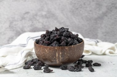 Dried black grapes on stone background. Dried grapes in coconut bowl. Nuts varieties. Healthy eating. close up