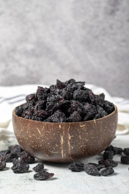 Dried black grapes on stone background. Dried grapes in coconut bowl. Nuts varieties. Healthy eating. close up
