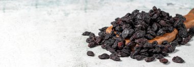 Dried black grapes on stone background. Dried grapes on a wooden serving board. Nuts varieties. Healthy eating. Empty space for text. Copy space