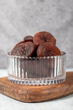 Dried apricots on stone background. Dark dried apricots in a glass bowl. Diet foods. close up